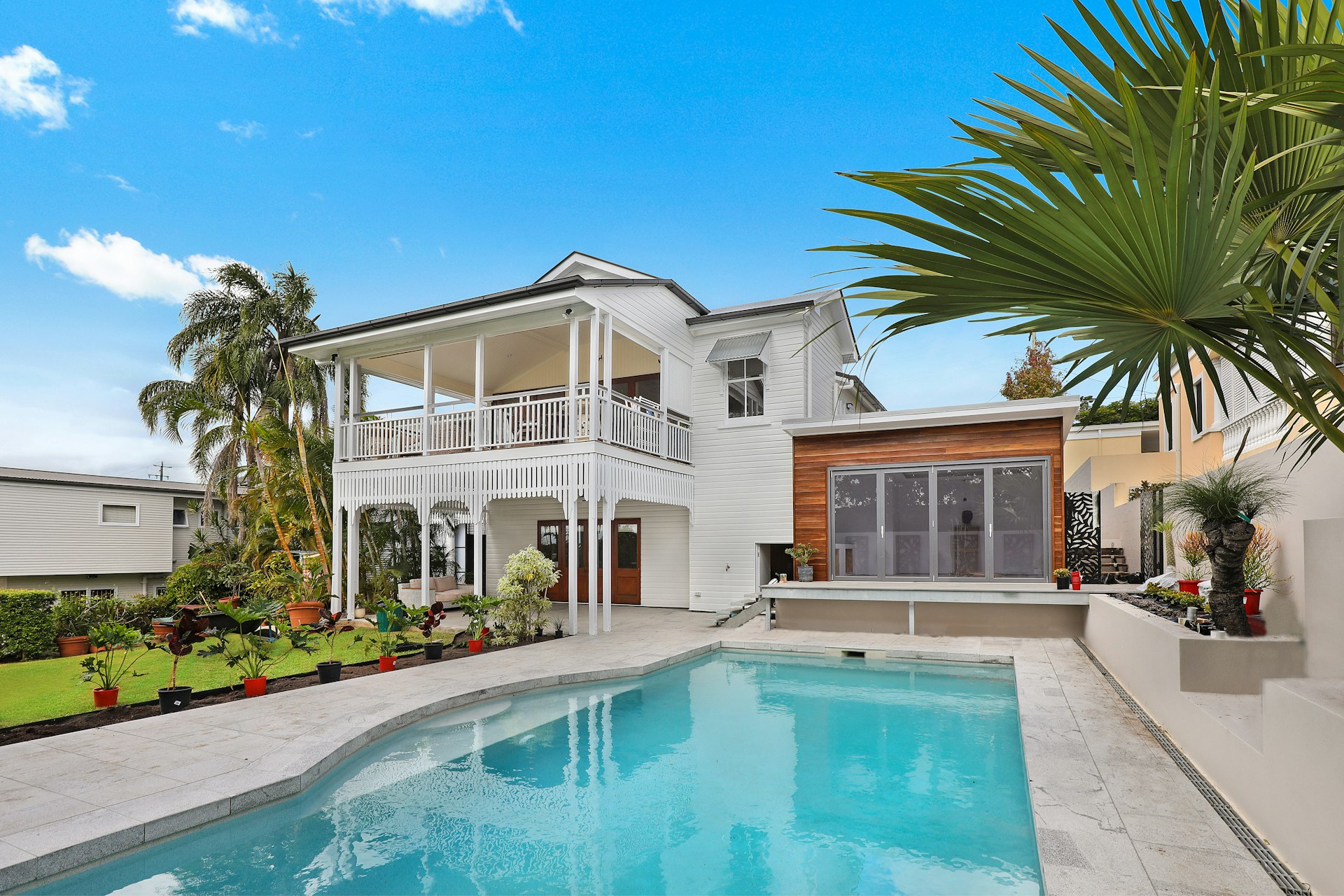 White two-story coastal-style home with a covered porch and pool