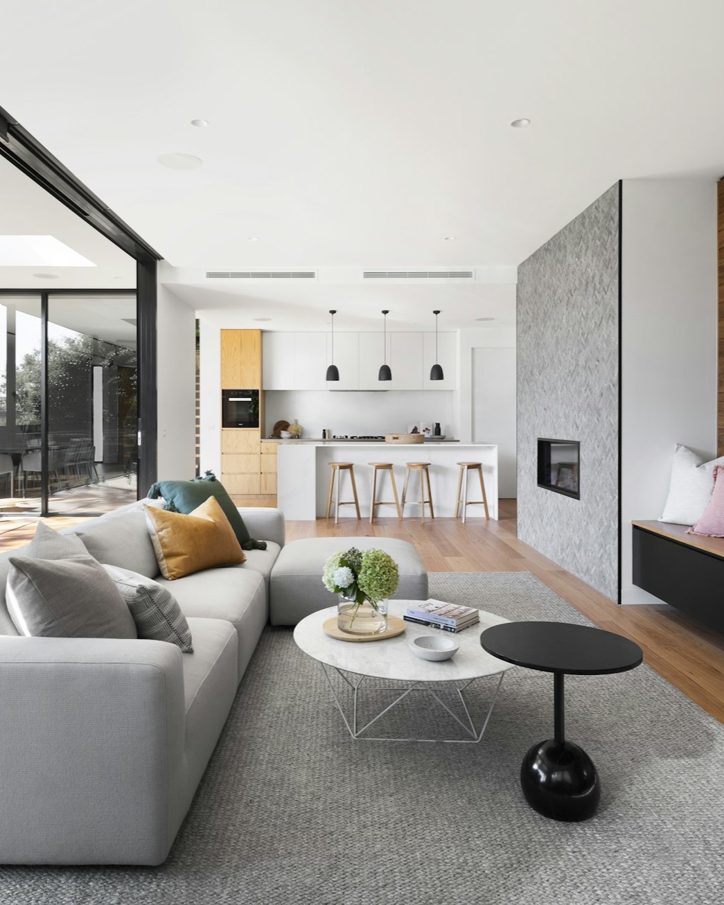 Bright modern open-plan interior with white kitchen, island seating and large windows